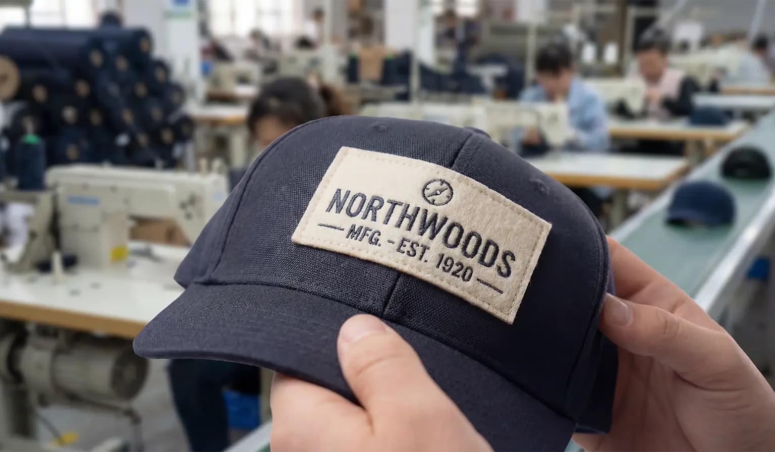 Custom embroidered patch stitched onto a cap on the production floor, made in bulk for brands and teams